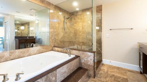 基拉戈122 Mariners Club的带浴缸和玻璃淋浴间的浴室。