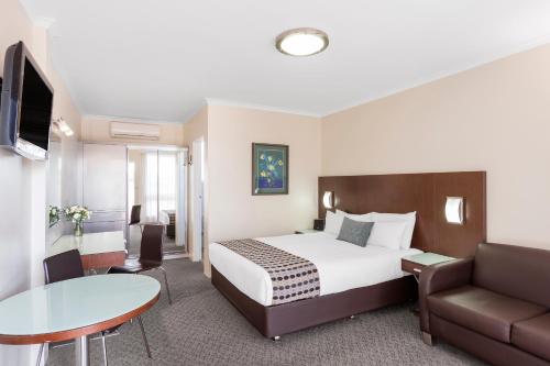 昆比恩BreakFree Queanbeyan的酒店客房配有床、沙发和桌子。