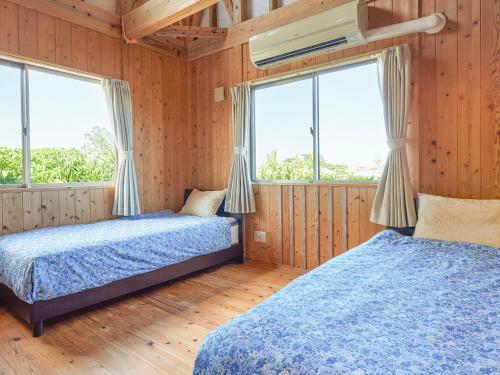 宜野座斯纳敦度假屋的配有木墙和窗户的客房内的两张床