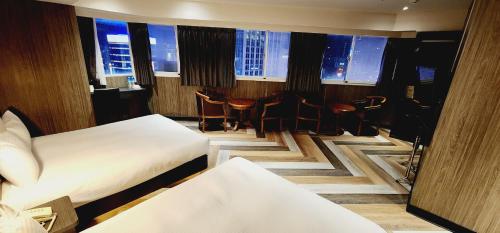 台北Gugis Inn 的酒店客房带两张床和一张桌子以及椅子。