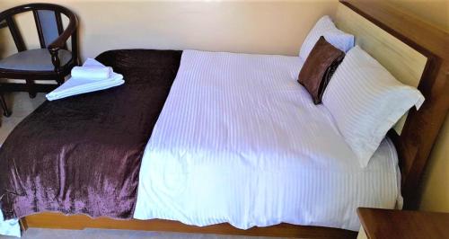 BulbulaWayu Nova Guesthouse的一间卧室配有一张带白色床单和椅子的床