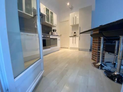 格拉斯Spacieux 3 pièces avec terrasse - Parking的厨房铺有木地板,配有白色橱柜。