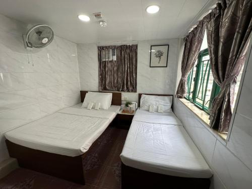 香港Mandarin Guest House的带2扇窗户的小客房内的2张床