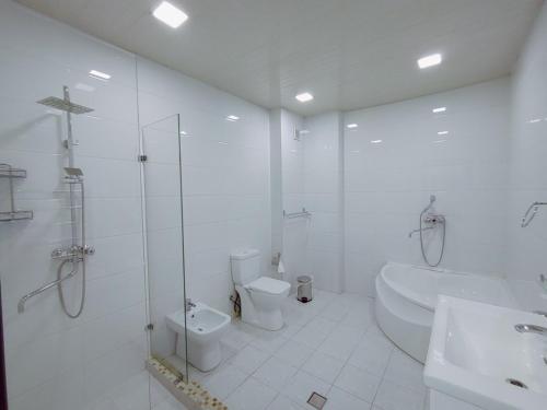 塔什干IZZA PALACE Hotel的带淋浴、卫生间和盥洗盆的白色浴室