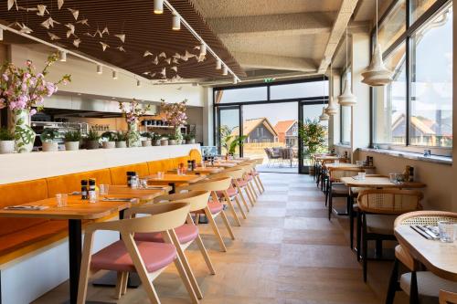 尼乌弗利特Dormio Resort Nieuwvliet-Bad的餐厅里一排桌椅