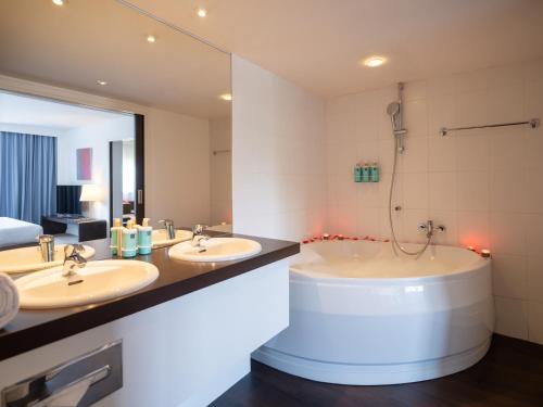 南特诺富特南特中心火车站酒店的浴室配有两个盥洗盆和浴缸。