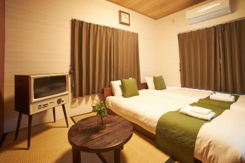 东京Kagurazaka Retro BAR & HOTEL的一间酒店客房,设有两张床和电视