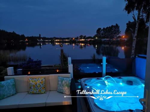 塔特舍尔Meridian Tattershall Lakes Escape - Lakeside lodge caravan with a fishing peg LUXURY HOT TUB的阳台设有按摩浴缸,俯瞰着湖泊