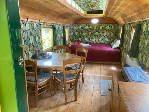 WilpEcostay de Wildernis的一间设有桌子的房间和一张位于拖车内的床铺