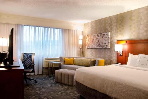 沃特伯里沃特伯里市中心万怡酒店的酒店客房配有一张床、一张沙发和一张书桌。