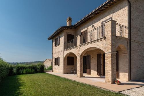 奥菲达Agriturismo San Nicolino的一座大型砖砌建筑,设有阳台和庭院