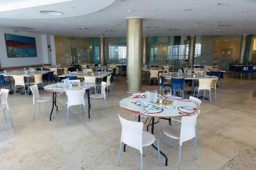 埃拉特阿迪酒店 的用餐室配有桌子和白色椅子