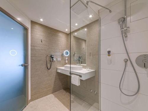 汉诺威汉诺威恩藤芳美居酒店的带淋浴、盥洗盆和镜子的浴室