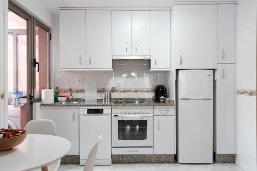 米尼奥UNA HABITACIÓN PLAYA GRANDE MIÑO的厨房配有白色橱柜和白色冰箱。