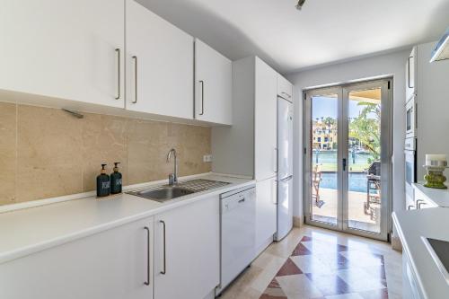 圣罗克Waterside Apartment in Sotogrande Marina with Private Pool的一间厨房,配有白色橱柜,享有游泳池的景色