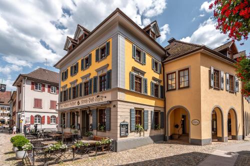 布赖斯高地区施陶芬stuub staufen的街道上一座黄色的建筑,配有桌椅