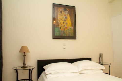 雅典Athens Quality Apartments - No4 - 1-bedroom apartment的卧室配有一张床,墙上挂有绘画作品