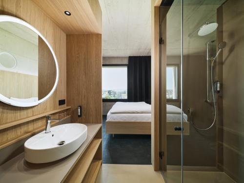 林茨Boulderbar Hotel Leonding的一间带水槽和淋浴的浴室以及一张床