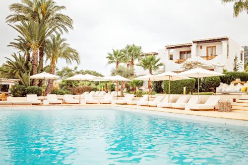 卡拉瓦德亚Petunia Ibiza, a Beaumier hotel的一个带躺椅和遮阳伞的游泳池