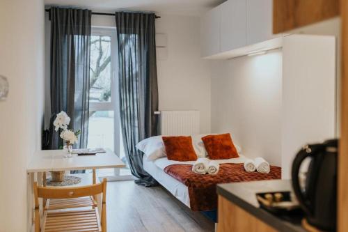 弗罗茨瓦夫Mikro Aparty bezpłatny parking的酒店客房设有一张床铺、一张桌子和一间厨房。