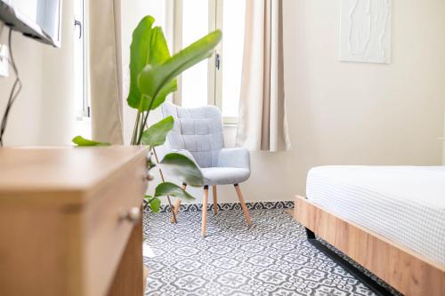 科斯镇Kosnian City Suites的一间卧室配有床、椅子和植物