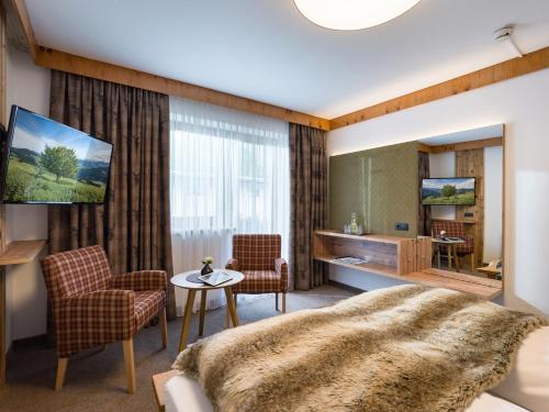 菲根Hotel Landhaus Zillertal的卧室配有一张床和一张桌子及椅子