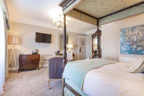 韦尔斯The Swan Hotel, Wells, Somerset的一间卧室配有一张天蓬床和梳妆台