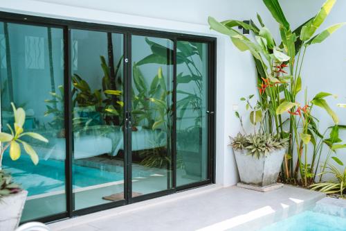 拉扬海滩度Layantara Resort, Phuket的一间玻璃门和盆栽的房间