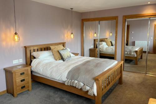 奥克尼Aurora - Self Catering, Kirkwall, Quiet Location with Luxury Hot Tub的一间卧室配有一张大床和镜子