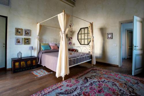 拉文纳Au petit jardin的一间卧室配有一张天蓬床和地毯。