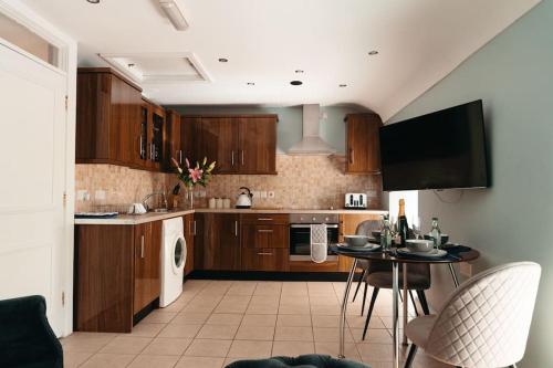恩尼斯基林Cottage Lawn Apartment的厨房配有木制橱柜、桌子和电视。