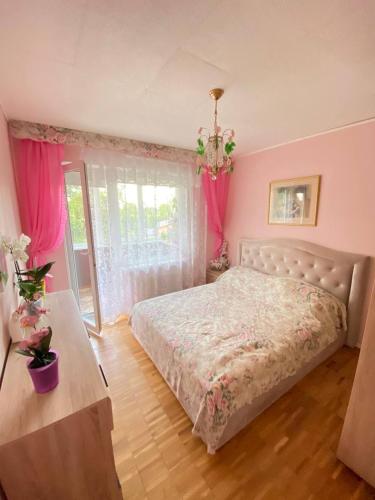 尤尔马拉Комната с лоджией у Татьяны的一间卧室配有床和一个带粉红色窗帘的窗户。