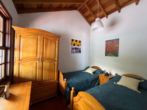 马佐Casa Los Calderos的一间卧室设有两张床和木制橱柜