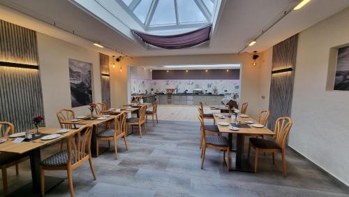 诺伊马根-德赫龙祖姆安科酒店的餐厅设有木桌和椅子,天窗