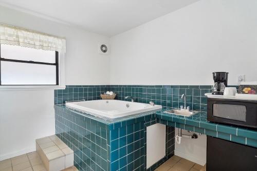 卡利斯托加Carlin's Cottage Court的蓝色瓷砖浴室设有浴缸和微波炉