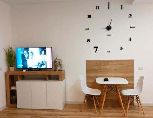 奥尔比亚Le pergole的客厅配有电视、桌子和时钟