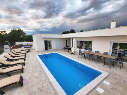 乌马格Villa Mare e Monti with heated pool的一座带游泳池、椅子和桌子的房子