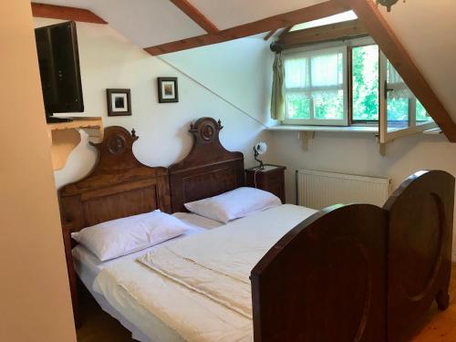 Mokrinetno kuća Đeram的一间卧室配有一张带木制床头板的床和一台电视。