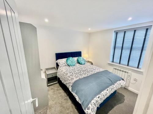普里茅斯New Modern Apartment With FREE Private Parking的一间卧室配有一张带蓝色床头板的床和窗户