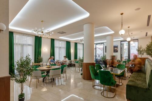 布德瓦Hotel Diplomat的一间设有绿色桌椅的餐厅,可容纳