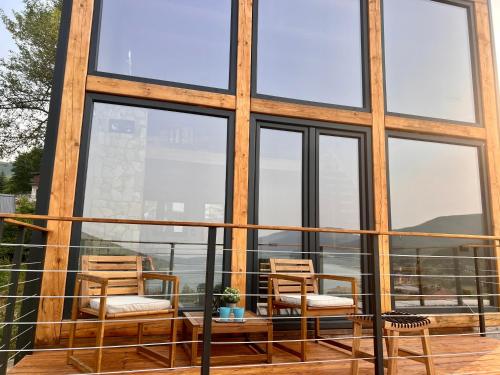 马夫罗沃Mount Log Cabin的阳台配有两把椅子和一张桌子,阳台设有窗户
