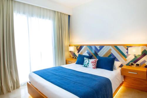 蓬塔卡纳Cana Rock Condos Penthouse Vista Espectacular Golf & Jacuzzi B-336 y B-330的一间卧室配有一张带蓝色床单的床和一扇窗户。