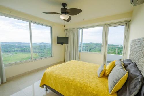 ArraijÃ¡n23o Penthouse Stunning Oceanview Resort Lifestyle的一间卧室配有一张带吊扇和窗户的床。