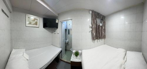 香港Mandarin Guest House的小房间设有两张床和电视