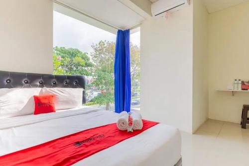 KendungRedDoorz @ Bukit Palma Surabaya的一间卧室设有大窗户和一张带拖鞋的床