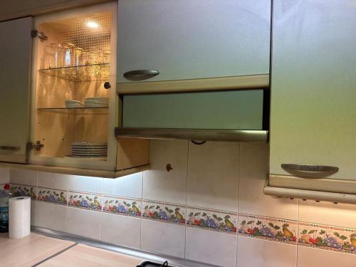 巴塞罗那Can Ginesta Muy feliz&tranquilo的厨房配有玻璃橱柜,内有餐具