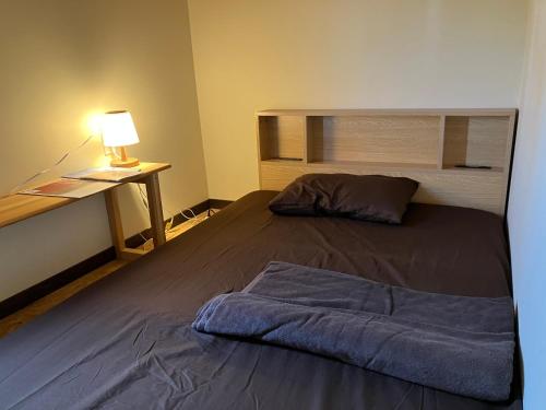 Noroshi九右衛門ゲストハウス(kuemon guesthouse)的一间卧室配有一张床和一张带台灯的书桌