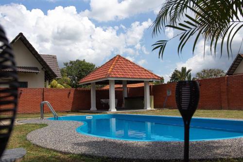 Kampong Alor GajahPoolhomestay Raudhah Intan的庭院内带凉亭的游泳池