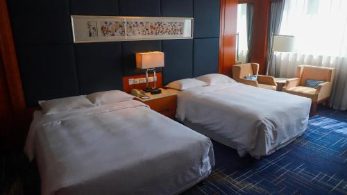 苏州苏州福朋喜来登酒店的酒店客房,配有两张床和椅子