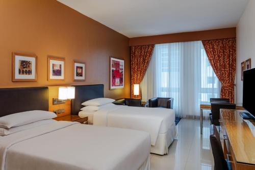 迪拜Four Points by Sheraton Bur Dubai的酒店客房设有两张床和电视。